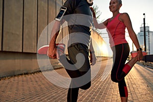 Great shape. Fitness couple in sports clothing warming up before running while standing outdoors