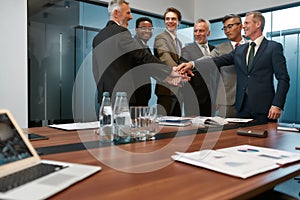 Great team. Close up of happy business people in formal wear holding hands together while standing in the modern office