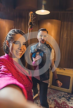 we are a great team, a singer girl and a guitarist taking a selfie in the recording studio