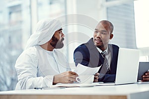 Great teamwork is what makes their business successful. two businessmen using a digital tablet and laptop while having a