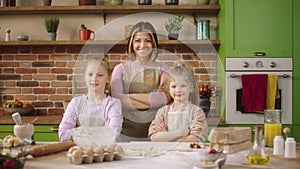 Great time spending at the kitchen posing in front of the camera happy smiling large mother and her two kids crossing