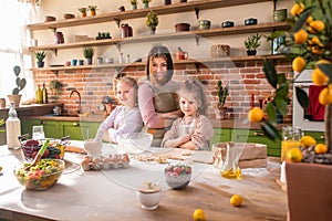 Great time spending at the kitchen posing in front of the camera happy smiling large mother and her two kids crossing