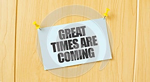 GREAT TIMES ARE COMING sign written on sticky note pinned on wooden wall