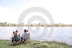 Great view of big river flowing. There is a family sitting by its shore and enjoying the moment. They are holding kids