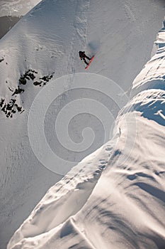 Great view of mountain slope covered with white powdery snow along which freerider on snowboard moves down