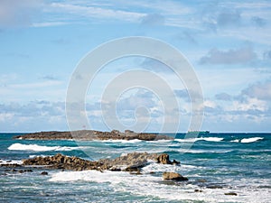 Great view of the sea, a little island and a boat on a beautiful windy day at Condado beach, San Juan, Puerto Rico