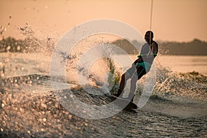 Great view of splashing wave and cheerful man energetically riding wakeboard.