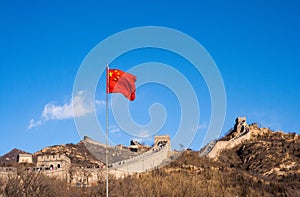 Great Wall of China with Chinese flag waving against a blue sky