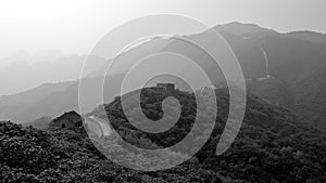 The great wall protecting the frontier through the mountains surrounded by dense forest, Mutianyu section, Beijing, China. Black