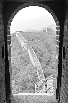 The great wall watched from a guard post. Framed by a gate from the observation post. Stairs saving a huge unevenness. Mutianyu