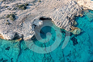 Greece, Cyclades. Aerial drone view of steep rocky coastline over green emerand sea water