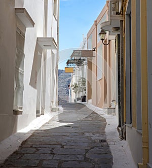 Greece, Cyclades. Andros island, Chora. Empty alley traditional wall blue sky background. Vertical