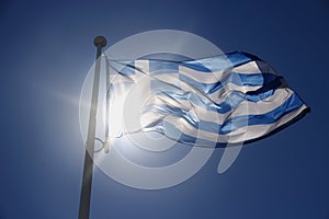 Greece flag on blue sky, backlit subject
