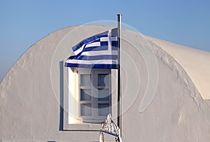 Greece flag on sunset light in Oia, Santorini island.