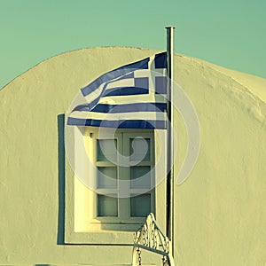 Greece flag on sunset light in Oia, Santorini island.