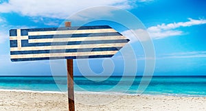 Greece flag on wooden table sign on beach background. It is summer sign of Greece