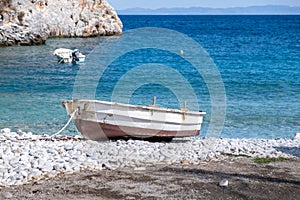 Greece. Pebble beach, moored boat calm sea, Mani Laconia, Peloponnese crystal clear water