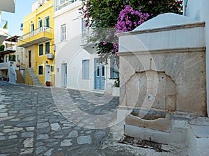 Greece Tinos island, Chora town. Cyclades street faucet, cobblestone street, bougainvillea