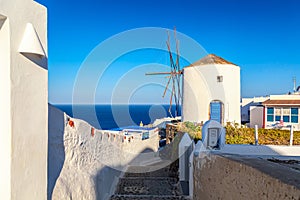 Greece vacation iconic background. Famous windmill in Oia village with traditional white houses during summer sunny day Santorini