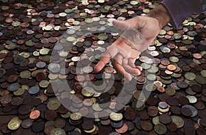 Greediness for money concept, coins background with stretching hand, finance, expenses, savings