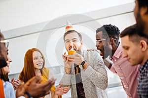 Greedy guy is trying to bite a bigger peace of cake in front of friends