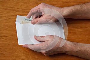 Greedy hairy man`s hands takes a bribe of some US dollars banknotes in the office at the table