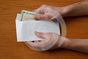 Greedy hairy man`s hands takes a bribe of some US dollars banknotes in the office at the table