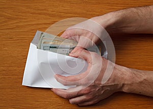 Greedy hairy man`s hands takes a bribe of some US dollars banknotes in the office at the table