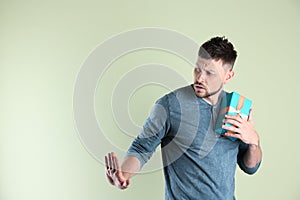 Greedy man hiding gift box on light background, space for text