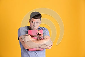 Greedy man hiding gift box on yellow background, space for text