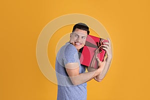 Greedy man hiding gift box on yellow, space for text