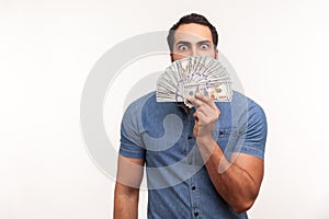 Greedy mercantile man hiding face behind fan of hundred dollar bills, enjoying smell of illegally earned money