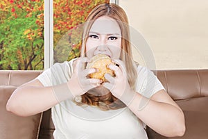 Greedy overweight woman eats burger