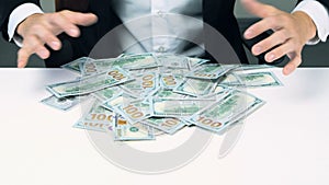 Greedy unrecognizable businessman hands grabbing lot of hundred dollar bills.