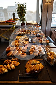 Greek breakfast buffet table full with varieties of pastries, buns, pancakes, donuts, butter cake, pizza, pies, boiled eggs, etc.