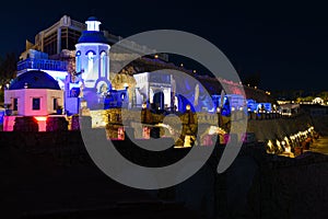 Greek cafe illuminated at night on a rocky seashoreGreek cafe illuminated at night on a rocky seashore