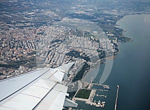 The Greek city of Thessaloniki from the airplane. You can see the silvery wing of the aircraft, the Aegean sea.