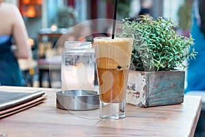 A greek cold coffee, freddo cappuccino placed on a wooden table outdoors.