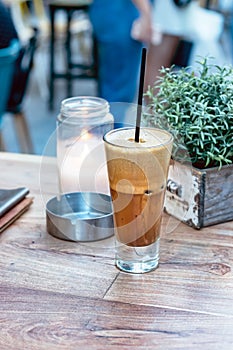 A greek cold coffee, freddo cappuccino placed on a wooden table outdoors.