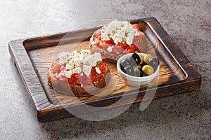 Greek dakos appetizer with barley rusk, tomatoes, feta cheese, oregano and olive oil closeup on the wooden board. Horizontal