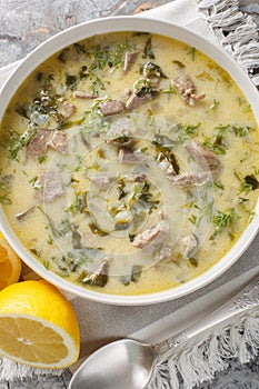 Greek Easter soup Magiritsa with lamb offal, herbs, seasoned with egg and lemon sauce close-up in a bowl. Vertical top view