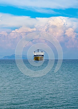 Greek ferry sailing in the Ionian Sea to the island of Kefalonia against the background of cumulus clouds