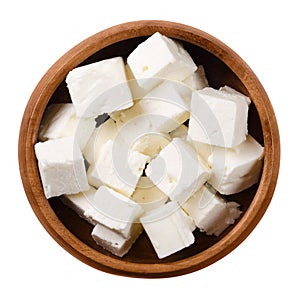 Greek Feta cheese cubes in wooden bowl over white