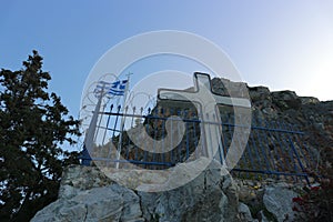 Greek flag behind barbed wire and a cross.