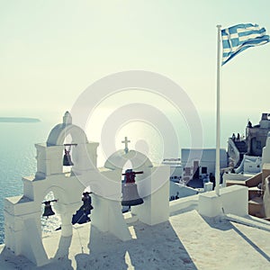 Greek flag and bell tower in Oia village, Santorini, Greece