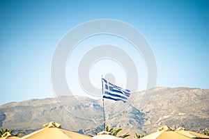 Greek flag with blue sky and mountains in background