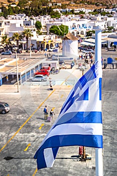 Greek flag over Paros harbor with wind mill, Cyclades, Greece. Theme of Cyclades.