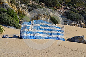 Greek flag painted on a rock. Tsambika beach on the island of Rhodes