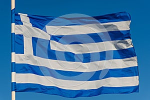 Greek flag on pole waving over blue background