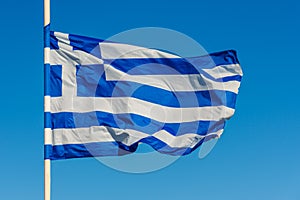 Greek flag on pole waving over blue background